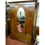 An Edwardian inlaid mahogany wardrobe with single central oval mirrored door and single drawer below