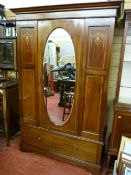 An Edwardian inlaid mahogany wardrobe with single central oval mirrored door and single drawer below