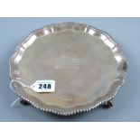 A circular silver letter tray with feather edged border on four ball and claw supports with