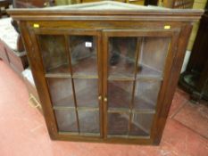 An antique pine hanging corner cupboard with two six pane opening doors with brass knobs and
