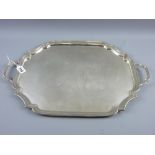 An oblong uninscribed silver tray with shaped corners and end handles, 59 ozs, Birmingham 1954