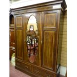 An Edwardian mahogany and line inlaid triple wardrobe, a stepped cornice over two twin panelled