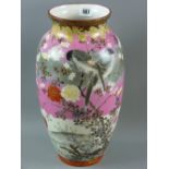 A large Japanese Kutani vase depicting birds, flowers and blossom on a pink, grey and white