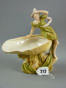 A Royal Dux figurine of a young lady seated on a shell dish, model no. 818 to the base, 19 cms high
