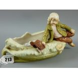 A Royal Dux figurine of a young boy seated on an oval dish, 13 cms high