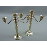 A pair of circular based twin branch single sterling silver candelabra, the bases having gadrooned