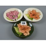 Three Moorcroft pin dishes - Magnolia on a cream ground, Hibiscus on a cream ground and Hibiscus