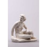Skulptur. Weiß glasiertes Steingut. Sitzender, weiblicher Akt auf ovalem Natursockel. H: 30 x 30 cm.