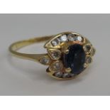 A ladies dress ring having an oval sapphire within a decorative diamond surround on a yellow metal