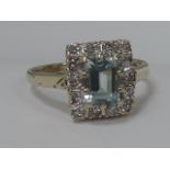 A ladies dress ring having an emerald cut blue topaz and diamond square cluster on a 9ct gold loop