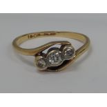 A ladies three stone diamond crossover ring on a yellow metal loop stamped 18ct