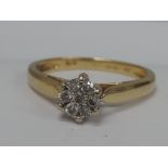 A ladies dress ring having a diamond daisy cluster in a raised claw setting with open shoulders on