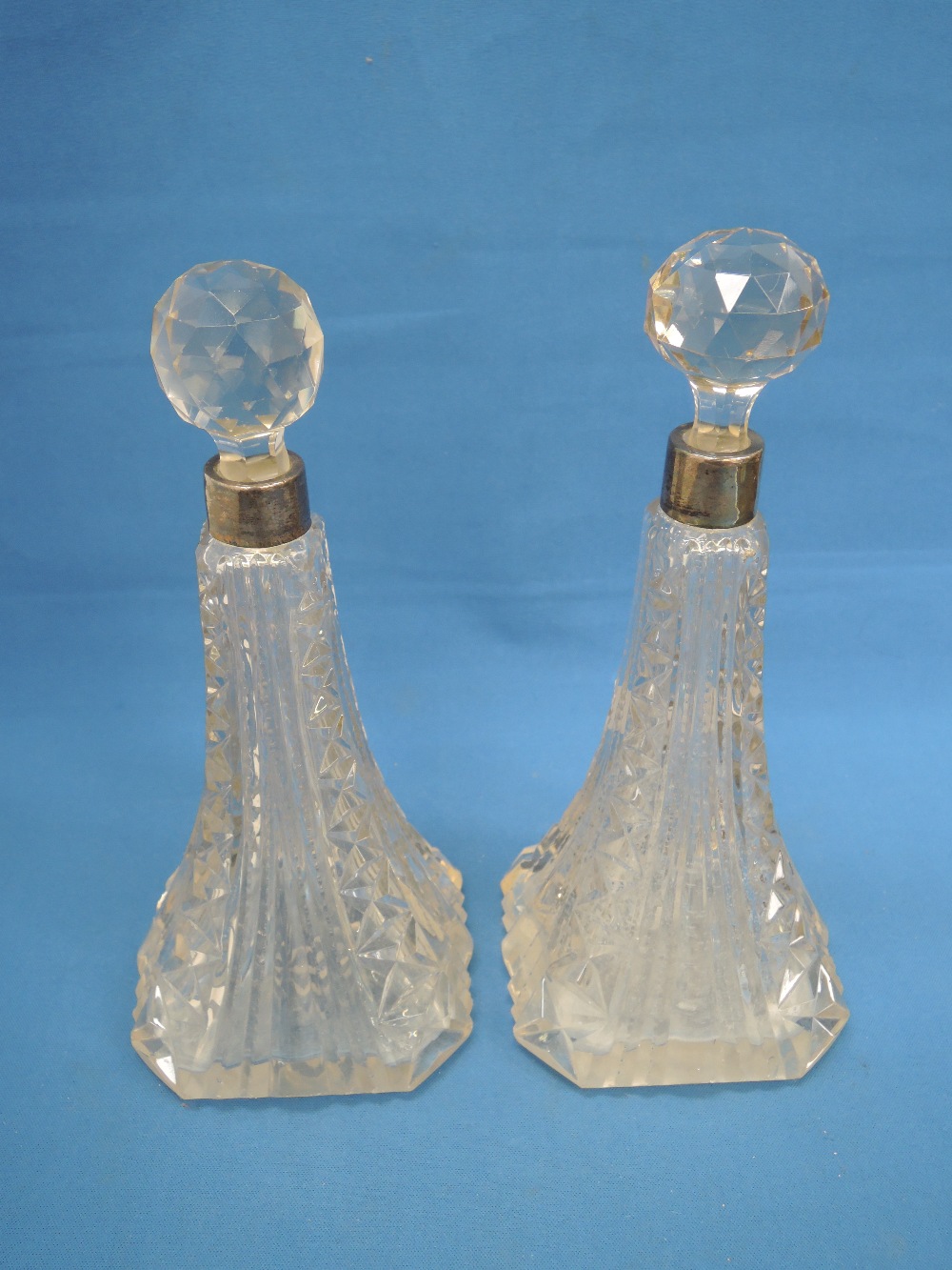 A pair of moulded glass scent bottles of tall tapered form having cut glass stoppers and HM silver