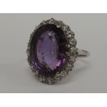 A ladies dress ring having a large oval amethyst style stone with diamond chip surround in a