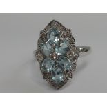 A ladies dress ring having six blue topaz oval cut stones with diamond decoration within a diamond