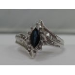 A ladies dress ring having a marquise cut sapphire in a raised claw mount with diamond double chanel