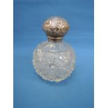 A cut glass perfume bottle having an HM silver collar and lid with repousse scroll decoration (AF)