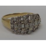A ladies dress ring having a large baguette and brilliant cut diamond oval raised cluster, approx