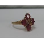 A ladies dress ring having four oval rubies in a claw set collared mount on a 9ct gold loop