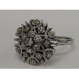 A ladies dress ring having a diamond chip cluster in stylised form in  a raised basket mount on an