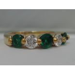 A ladies dress ring having three emeralds interspersed by two diamonds in a moulded collared mount