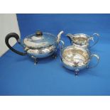 A three piece silver tea set of circular squat form on paw feet having hard wood knop and handle,