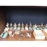 A shelf of cold cast military figures on horseback and horses including Rose models