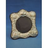 A silver photograph frame of circular form having extensive repousse cherub and scroll decoration