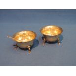 A pair of silver salts of circular form having shaped rims and trefoil feet with matching spoon