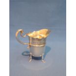 A small silver cream jug of helmet form on trefoil paw feet, with shaped rim and moulded  handle,