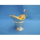 A Victorian silver cream jug of helmet form having oval pedestal foot, loop handle and shaped rim,