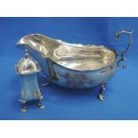 A silver sauce boat of plain form having scalloped edge, loop handle and trefoil paw feet, Sheffield