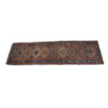 A NORTH WEST PERSIAN WOOL RUNNER, c. 1900, the red and navy ground woven with interlinked lozenges
