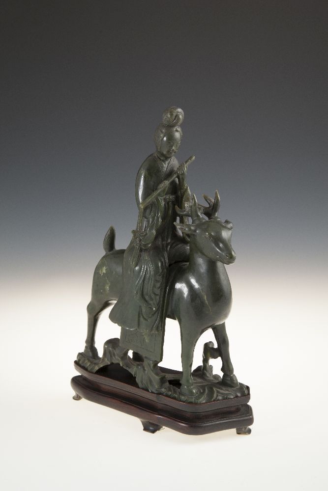 A CHINESE SPINACH JADE GROUP, 19th/20th Century, of female deity riding a stag, the figure seated to