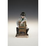 A VIENNA PORCELAIN PAINTED FIGURE OF THE DEFEATED NAPOLEON seated on a chair in contemplation.