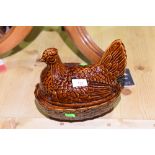 A brown glazed pottery hen egg basket