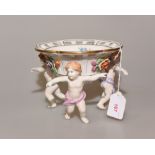 An early 20th century Continental porcelain comport with pierced bowl supported by three cherubs,