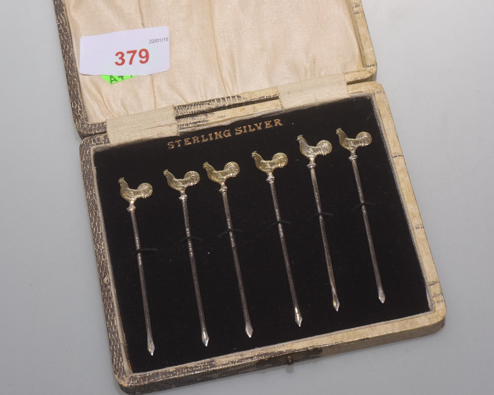 A cased set of six silver picks each with a gilt silver cockerel terminal, stamped Sterling Silver
