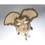 A lady's Venetian gold and cream painted full-face mask with stick, applied with gilt thread