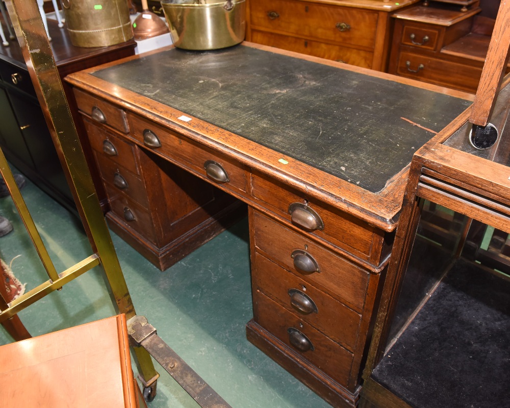 An early 20th century oak leather inset pedestal desk