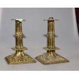 A pair of gilt brass candlesticks with square moulded drip trays above reeded columns and relief