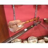 A tribal club, the handle inlaid with mother of pearl; together with a tribal stringed instrument,