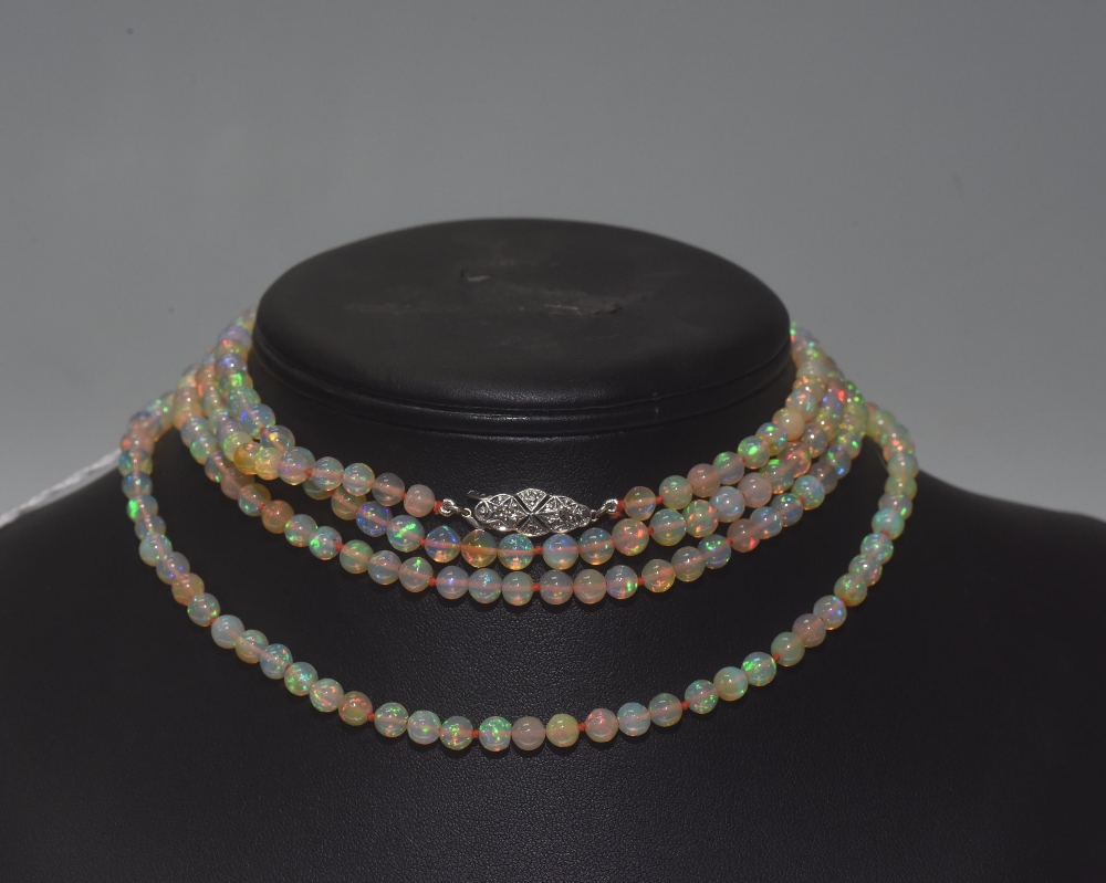 A long single strand opal bead necklace, on a diamond-set clasp. Length approx. 1.40 metres