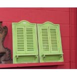 A pair of green painted shabby chic shuttered mirrors, each fitted with a shelf