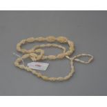 An early 20th century ivory necklace, of graduated oval floral-carved beads, on a barrel clasp.