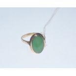 A 14ct gold jadeite ring, the oval jadeite cabochon collet-set on a pierced scroll cast mount on a