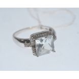 An aquamarine and diamond ring, the square cut aquamarine within a bezel of diamonds on diamond