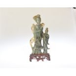 A Chinese carved green hardstone figure group, poss. spinach jade, on a hardwood stand. Height 24cm