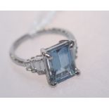 An aquamarine and diamond ring, the large emerald cut aquamarine flanked by stepped baguette cut