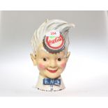 A novelty Coca-Cola cold painted money box in the form of a blond haired boy with  blue bow tie with